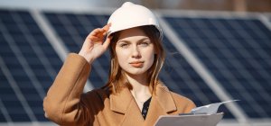 Técnica en Eficiencia Energética con un casco y apuntes frente a placas solares